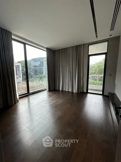 Spacious modern living room with large windows and wooden flooring