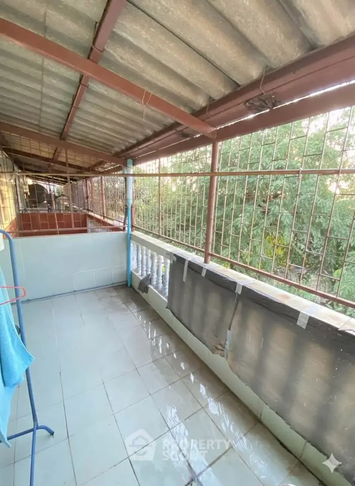 Spacious balcony with tiled flooring and partial tree view