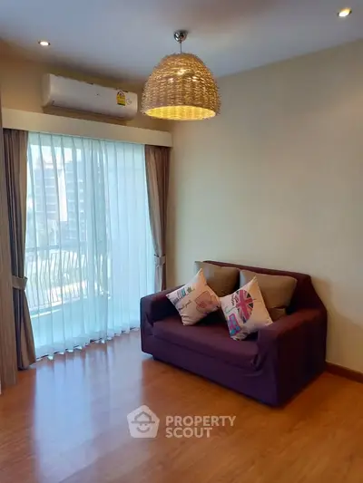 Cozy living room with modern decor and large window offering natural light.