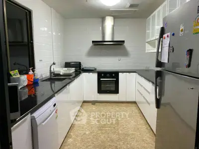 Modern kitchen with sleek white cabinets and built-in oven in a cozy apartment.