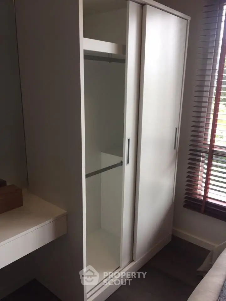 Modern bedroom with sleek white wardrobe and natural light from window blinds.