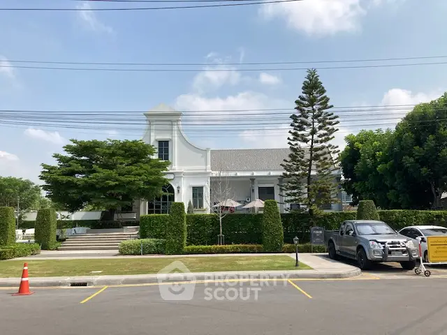 Elegant suburban house with manicured garden and driveway, showcasing classic architecture and lush greenery.