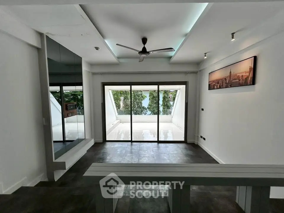 Modern living room with large glass doors leading to a balcony with a scenic view.