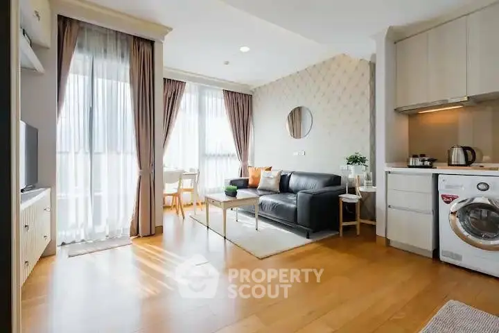 Modern living room with open kitchen, featuring sleek furniture and natural light.