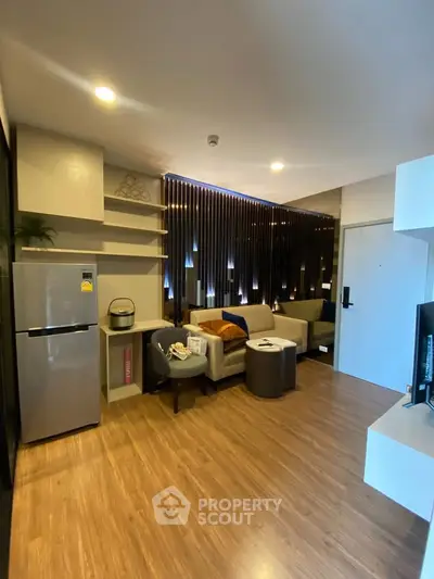 Modern living room with stylish decor and wooden flooring, featuring a cozy seating area and sleek appliances.