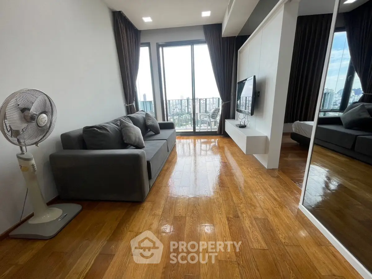 Modern living room with wooden floors, large windows, and city view.