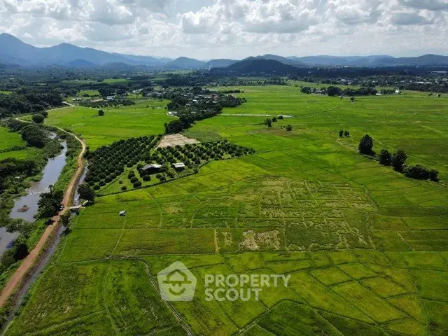 Expansive aerial view of lush green fields and distant mountains, perfect for agricultural investment.