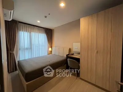 Cozy bedroom with modern furnishings and ample natural light from large window.