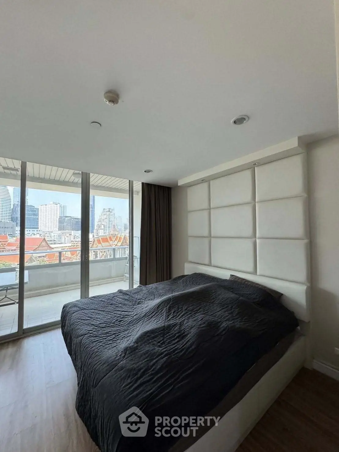 Spacious bedroom with city view and large windows in modern apartment