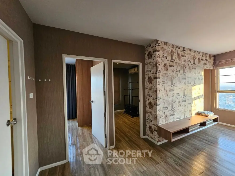 Spacious living room with stylish wallpaper and hardwood flooring, featuring ample natural light and a modern aesthetic.