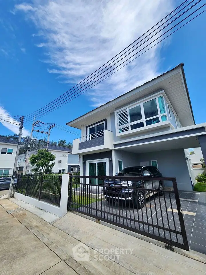 Modern two-story house with carport and lush green lawn under clear blue sky