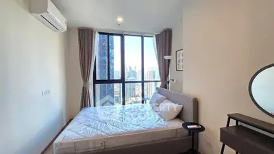 Modern bedroom with city view, large windows, and stylish decor in a high-rise apartment.