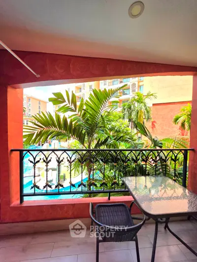 Charming balcony with lush greenery and pool view in a vibrant residential complex.