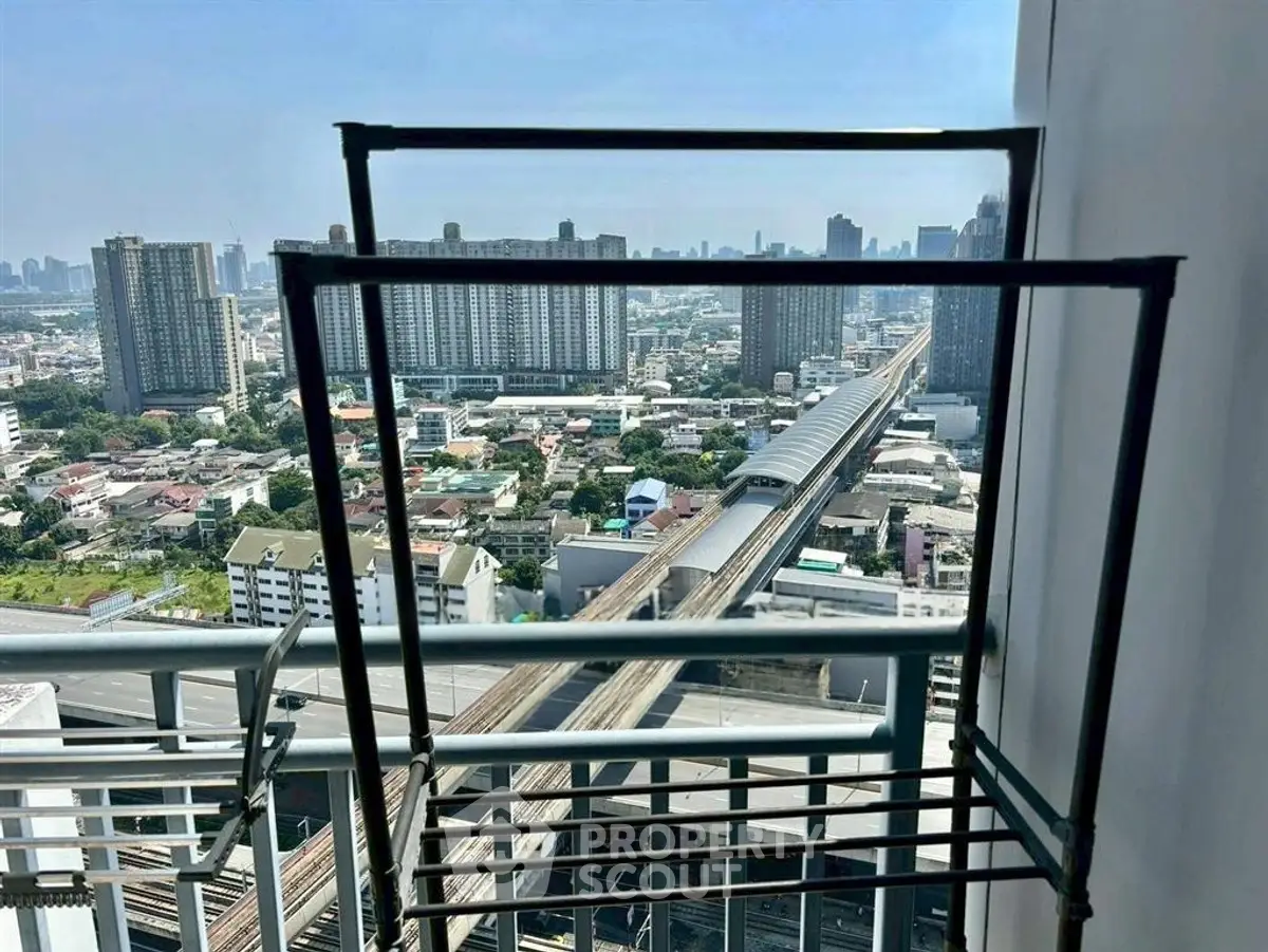 Stunning cityscape view from high-rise balcony overlooking urban skyline and train tracks.