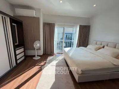 Spacious bedroom with modern decor and large window offering natural light