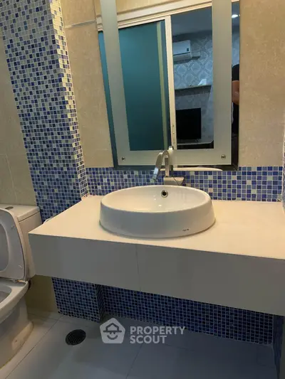 Modern bathroom with stylish blue mosaic tiles and sleek white fixtures.