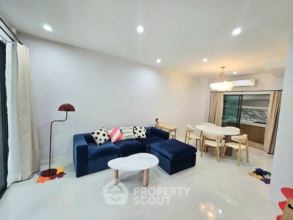 Spacious modern living room with elegant navy sofa and chic dining area, perfect for stylish urban living.