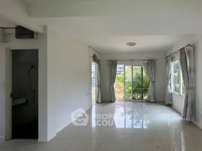 Spacious living room with large windows and garden view, perfect for natural light lovers.