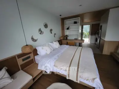 Spacious bedroom with modern decor and open layout leading to a kitchen area.
