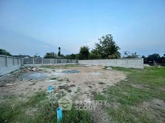 Spacious vacant land plot with boundary walls, ideal for development.