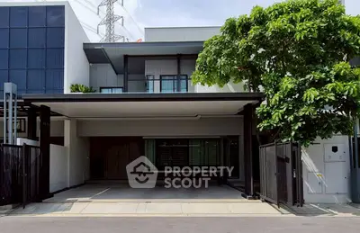 Modern two-story house with spacious driveway and lush greenery.