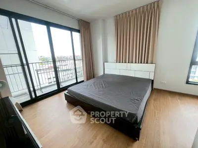 Spacious bedroom with large windows and balcony access in modern apartment.