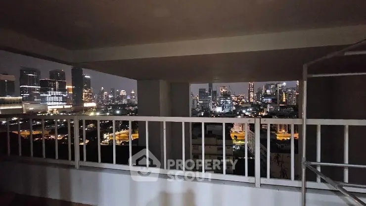 Stunning cityscape view from a high-rise balcony at night, showcasing vibrant urban lights.