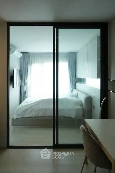 Modern bedroom with glass partition and stylish decor, featuring a cozy bed and elegant furnishings.