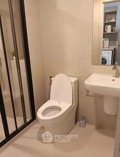 Modern bathroom with sleek fixtures and glass shower enclosure in a contemporary apartment.