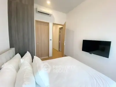 Modern bedroom with wall-mounted TV and air conditioning in a stylish apartment.