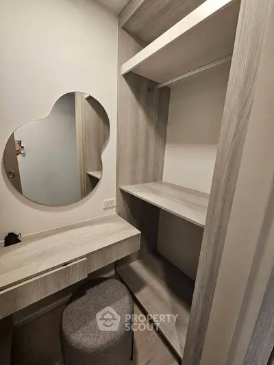 Modern walk-in closet with stylish mirror and seating in a contemporary apartment.