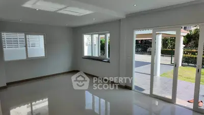 Spacious living room with large windows and sliding glass doors opening to a garden view.