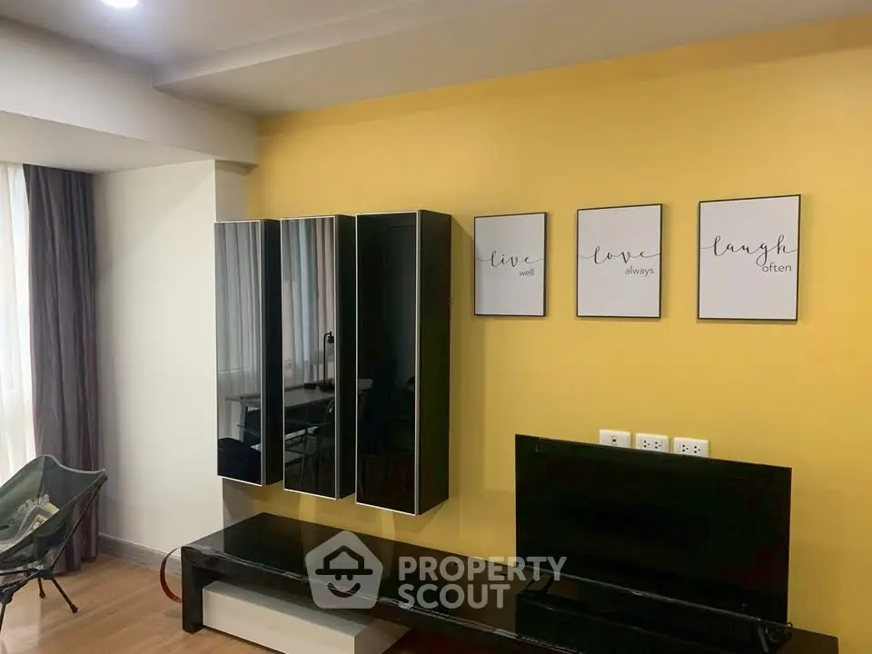Modern living room with stylish black furniture and yellow accent wall, perfect for cozy gatherings.