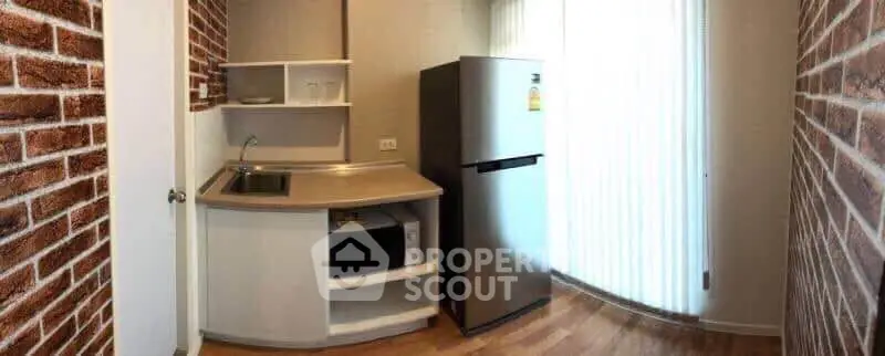 Cozy kitchen with modern fridge and brick accent walls, perfect for compact living spaces.