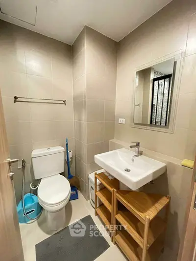 Modern bathroom with sleek fixtures and neutral tiles, featuring a compact design and functional layout.