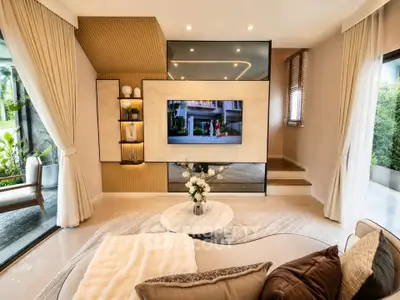 Luxurious living room with modern decor and large windows offering garden views.