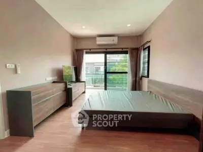 Spacious bedroom with modern furnishings and large windows offering natural light and a serene view.