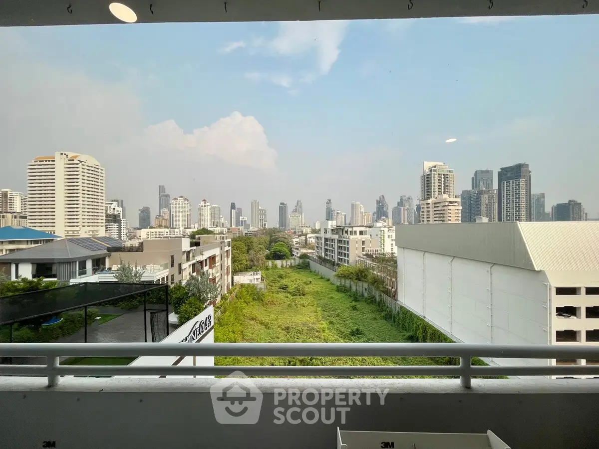 Stunning cityscape view from a high-rise balcony with lush greenery below.