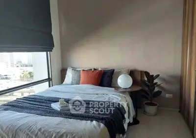 Cozy bedroom with large window and modern decor in urban apartment.