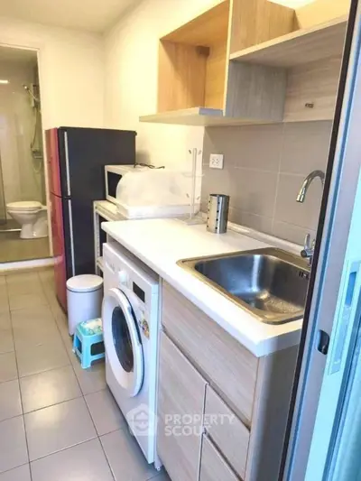 Compact kitchen with washing machine and modern appliances in cozy apartment.
