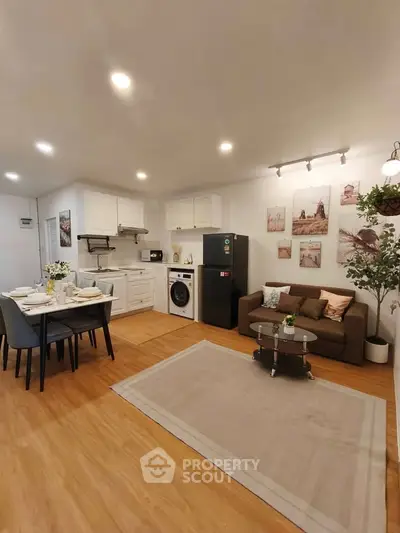 Modern open-plan living room with kitchen and dining area, featuring stylish decor and appliances.
