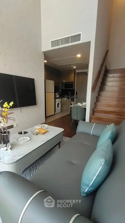 Modern living room with stylish sofa, TV, and open kitchen layout in a cozy apartment.