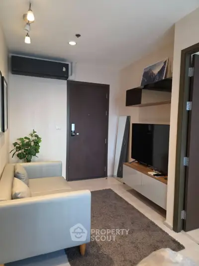 Modern living room with sleek furniture and wall-mounted TV in a cozy apartment.