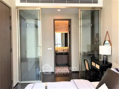 Modern bedroom with sliding glass doors leading to a luxurious bathroom featuring marble accents.
