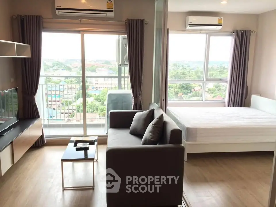 Modern studio apartment with balcony and scenic view, featuring cozy living area and air conditioning.