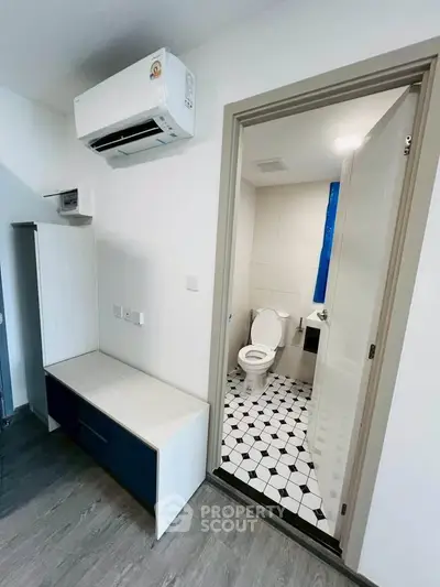Modern apartment with air conditioning and stylish bathroom featuring geometric floor tiles.
