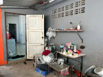 Rustic kitchen area with open shelving and assorted cookware, showcasing a functional and practical space.