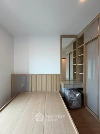 Modern minimalist bedroom with built-in wooden furniture and ample storage space.