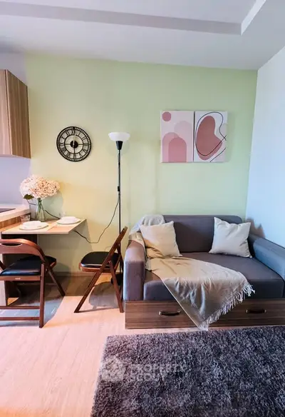 Cozy living room with modern decor, featuring a stylish sofa, wall art, and a compact dining area.