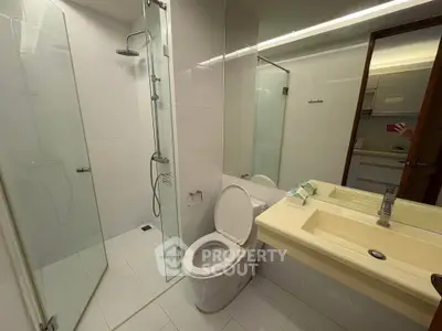 Modern bathroom with glass shower and dual sinks in sleek real estate property.